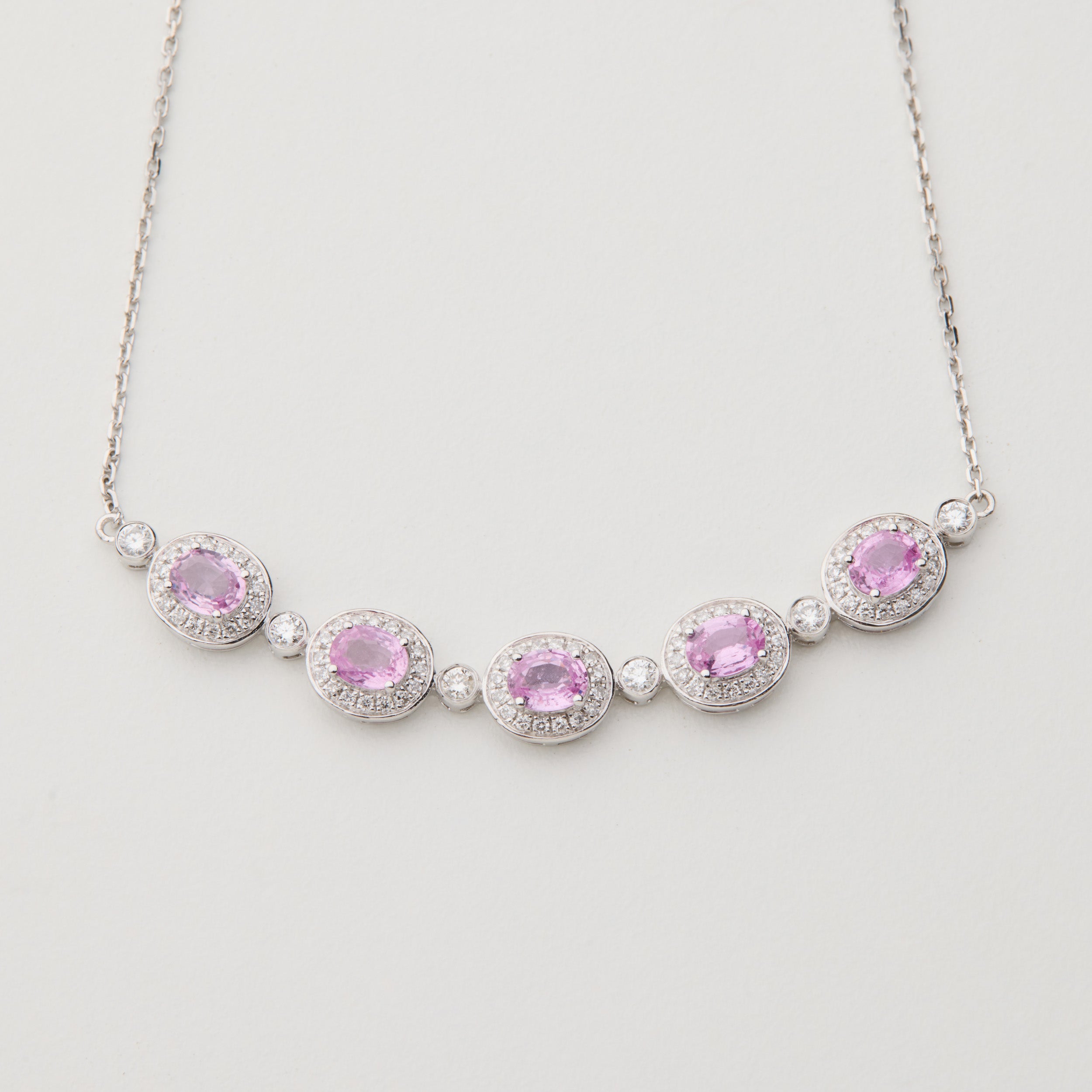 Aura Field necklace with oval Padparadscha pink sapphires and diamond halos in 18K white gold